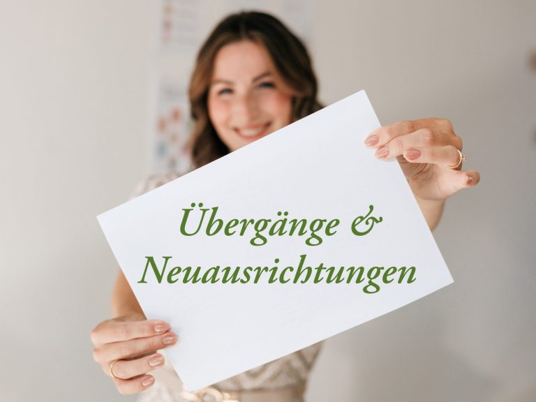Übergänge und Neuausrichtungen Coaching Frau hält ein Schild mit der Aufschrift "Übergänge & Neuausrichtungen".